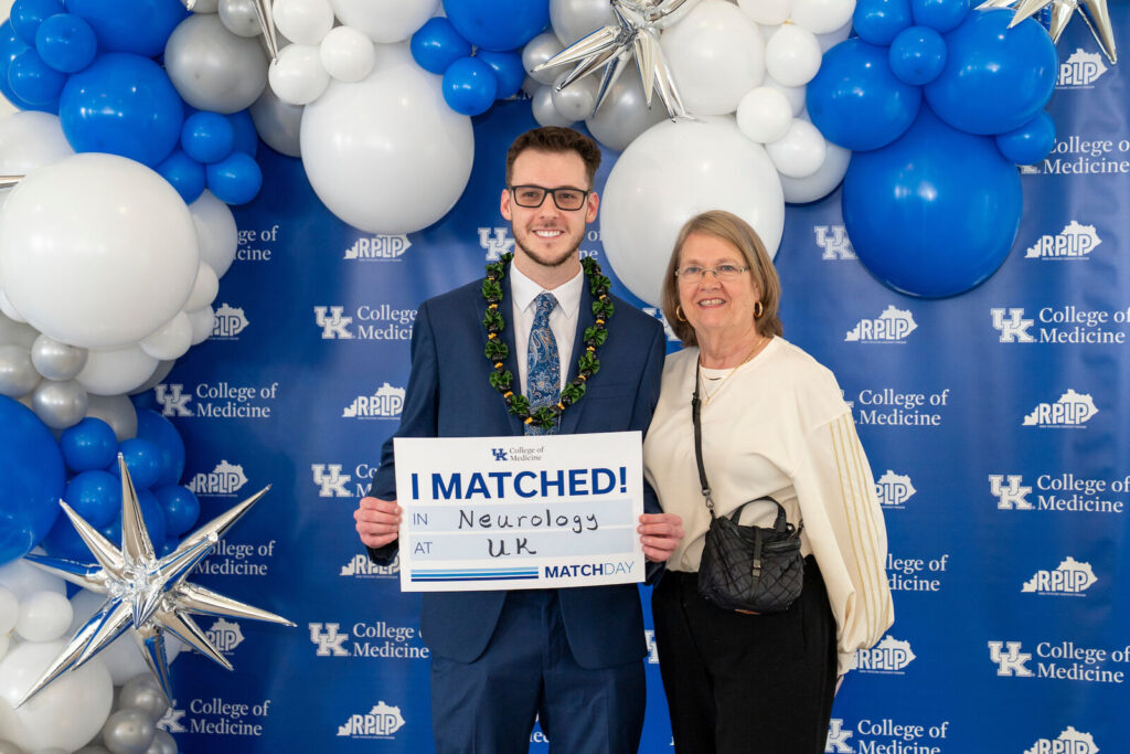 Dawson Stephens holds an I Matched sign for Neurology at UK while standing with his mother.