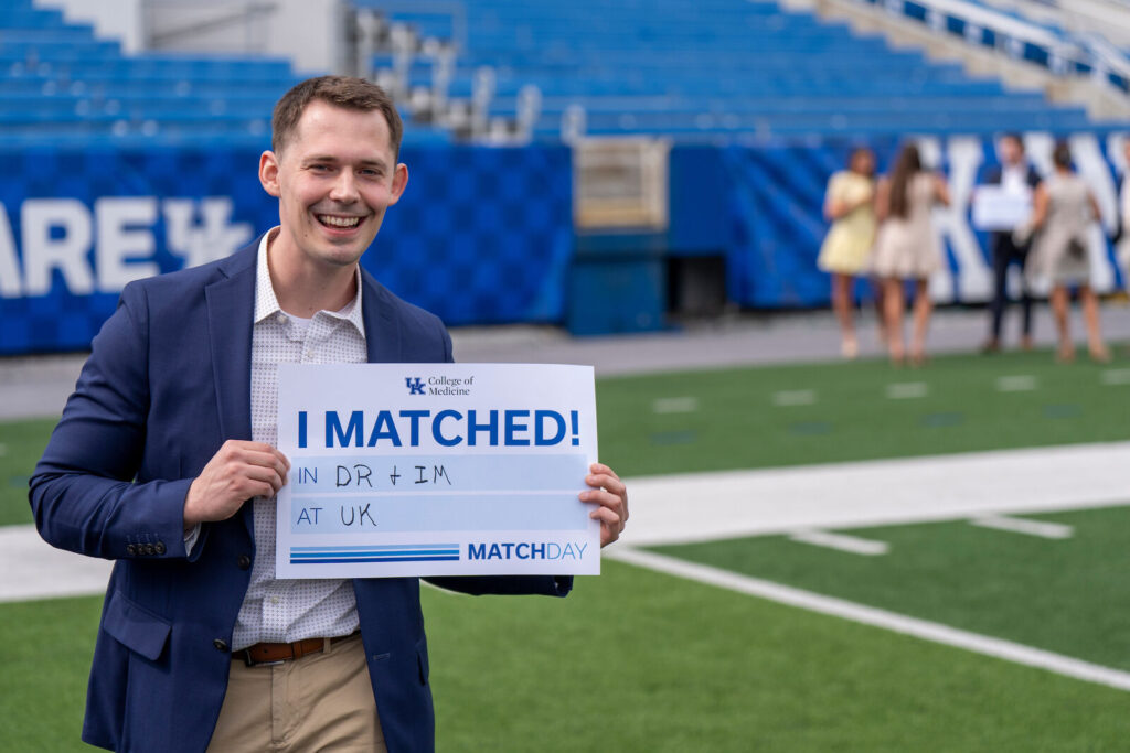 Rob Yates holds an I Matched sign for DR + IM at UK at Kroger Field.