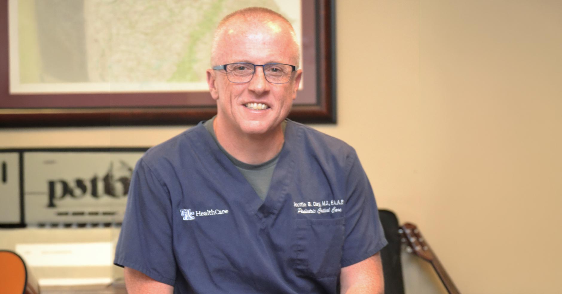 Scottie Day, MD, pediatric critical care specialist and physician-in-chief of Golisano Children's Hospital at UK HealthCare, in scrubs with his guitar nearby