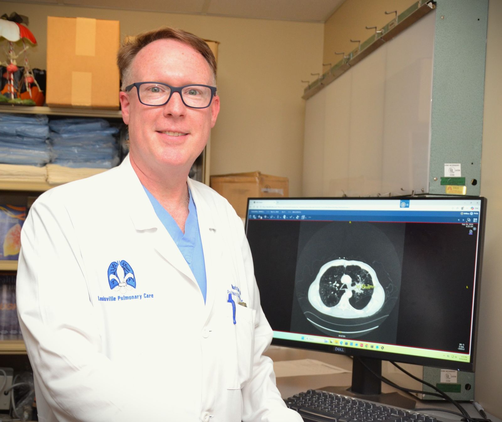 Mark Esterle, MD, beside a monitor showing a lung CT